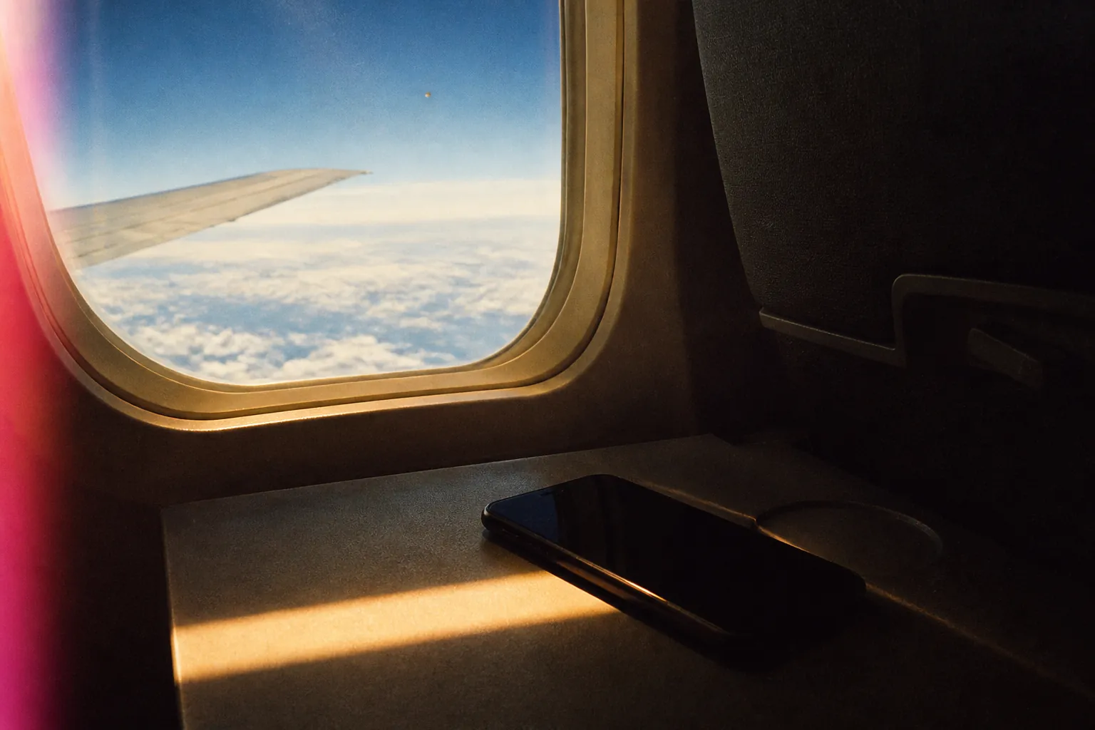 What is an eSIM: phone on an airplane tray in gold window light, analog film grain